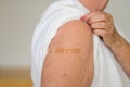 Anonymous lady showing the plaster covering her vaccination site