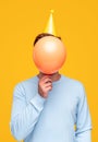 Anonymous man hiding face behind balloon