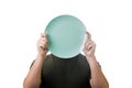 Anonymous man hiding his identity, covering face using an empty dish plate. Global crisis and hunger issue. Food supply problem. Royalty Free Stock Photo