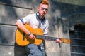 Anonymous man playing playing music with guitar on a city sidewalk. Street musician Royalty Free Stock Photo