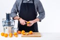 Anonymous man preparing fresh orange juice using electric juicer, healthy lifestyle detox concept on white background. Royalty Free Stock Photo