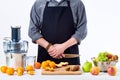 Anonymous man wearing an apron, preparing fresh fruit juice using modern electric juicer, healthy lifestyle detox concept on white Royalty Free Stock Photo