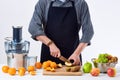 Anonymous man wearing an apron, preparing fresh fruit juice using modern electric juicer, healthy lifestyle detox concept on white Royalty Free Stock Photo