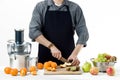 Anonymous man wearing an apron, preparing healthy freshly made fruit juice, using modern electric juicer, healthy lifestyle concep