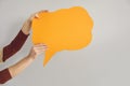 Anonymous person holding amber orange copy space speech bubble on gray background Royalty Free Stock Photo