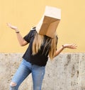 Anonymous person wearing a paper bag over her head in front of yellow background Royalty Free Stock Photo