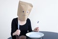 Anonymous sad woman with empty plat sit at the table alone