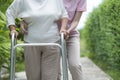 Senior woman walking by walker, she living with young female physical therapist nurse take care and support her Royalty Free Stock Photo