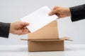 Anonymous submission process with hands placing white paper into cardboard box Royalty Free Stock Photo