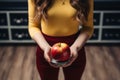 Anonymous woman checks weight, holds apple, emphasizing health and balanced lifestyle