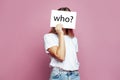 Anonymous woman covering face with white paper on pink background