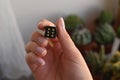 An anonymous woman holding a black cube with golden dots.