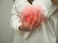 Anonymous woman touching her elbow, suferring from tendonitis, close up against grey