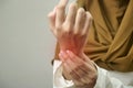 Anonymous woman touching her wrist, suferring from arthritis disease, close up against grey Royalty Free Stock Photo