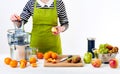 Anonymous woman wearing an apron, preparing fresh fruit juice using modern electric juicer, healthy lifestyle detox concept Royalty Free Stock Photo