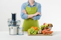 Anonymous woman wearing an apron, ready to start preparing healthy fruit juice using modern electric juicer