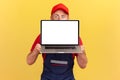 Anonymous worker man covering half of face with laptop computer with blank screen for promotion. Royalty Free Stock Photo