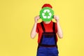 Anonymous worker woman standing hiding her face behind green recycling sign. Royalty Free Stock Photo