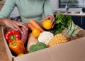 An anonymous young woman checks her fruit and veg delivery box Royalty Free Stock Photo