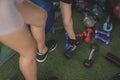 An anonymous young woman picks up a hex dumbbell lying on an artificial grass mat with other free weights. Working out at the gym Royalty Free Stock Photo