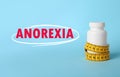 Anorexia concept. Bottle of weight loss pills with measuring tape on light blue background