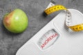 Anorexia concept. Scales, measuring tape and apple on grey background, flat lay