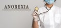 ANOREXIA - concept of text on gray background. Nearby is a doctor in white coat and stethoscope