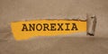 Anorexia word appearing behind brown torn paper. Eating disorders women healthcare concept