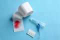 Anoscope, suppositories and toilet paper with red feather on light blue background, flat lay. Hemorrhoid treatment