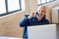 Another call from a happy client. a happy businessman answering his phone while working at his computer in the office. Royalty Free Stock Photo