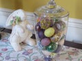 A jar of multicolored faux eggs and a fake white rabbit for a decoration?