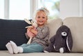 Another day to play with my toys. Full length portrait of an adorable little girl sitting alone on the sofa and playing Royalty Free Stock Photo