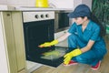 Another picture of woman cleaning inside of stove. She washes the door. Girl holds it with hands. She works alone.