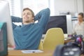 Another project done and dusted. a content young office worker leaning back in his chair with his hands behind his head.