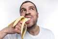Another strange picture of unshaved guy eating ripe banana. He is biting a big piece of fruit. Man is enjoying the