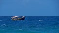 Small colored fishing boat on the troubled sea in the south of Mahe island near tropical beach.
