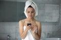 Confident positive young female using smartphone in bathroom texting message