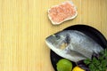 Seafood flat lay of sea fish, lemon, lime, basil, parsley and plates with pink Himalayan salt