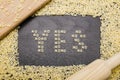 The answer yes made up of a set of words no, with small pasta letters on a dark background wooden board surrounded by other le Royalty Free Stock Photo