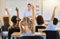 Answering, back and children raising hand in class for a question, answer or vote at school. Teaching, academic and a Royalty Free Stock Photo