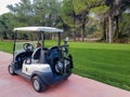 Antalya, Turkey, November 2019: a Golf Car with a bag of golf clubs on the track among the golf courses. Someone is sitting in the Royalty Free Stock Photo