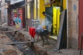 Street view of Madagascar, poor African country. Black man grills meat next to an open sewage Royalty Free Stock Photo