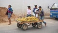 Antananarivo, Madagascar - April 24, 2019: Unknown Malagasy man, pulling cart with ripe bananas on main asphalt road, other women