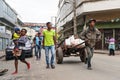 Antananarivo, Madagascar - April 24, 2019: Unknown Malagasy man pulling cart with white bags, woman with child on her hands