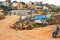 Antananarivo, Madagascar - April 24, 2019: Various automobile parts on red dust ground of small scrapyard near main road, trucks