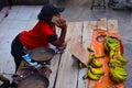 African girl selling bananas. Street vendor in Madagascar with bananas on orange banner of the president candidate Andry Rajoelina