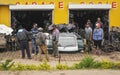 Antananarivo, Madagascar - May 07, 2019: Local Malagasy men standing and chatting in front of garage workshop with various cars