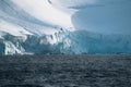 Antarctic expedition, cruise passengers in yellow parkas ride in a Zodiac inflatable boat, very close to a huge white Royalty Free Stock Photo