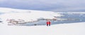 Antarctic tourists in red parkas climb an Antarctic iceberg landscape at Portal Point Antarktika