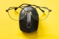 Anthropomorphism concept. Computer mouse with glasses on yellow background. Internet search with low vision, voice
